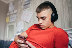 Teenager with headphones on bed
