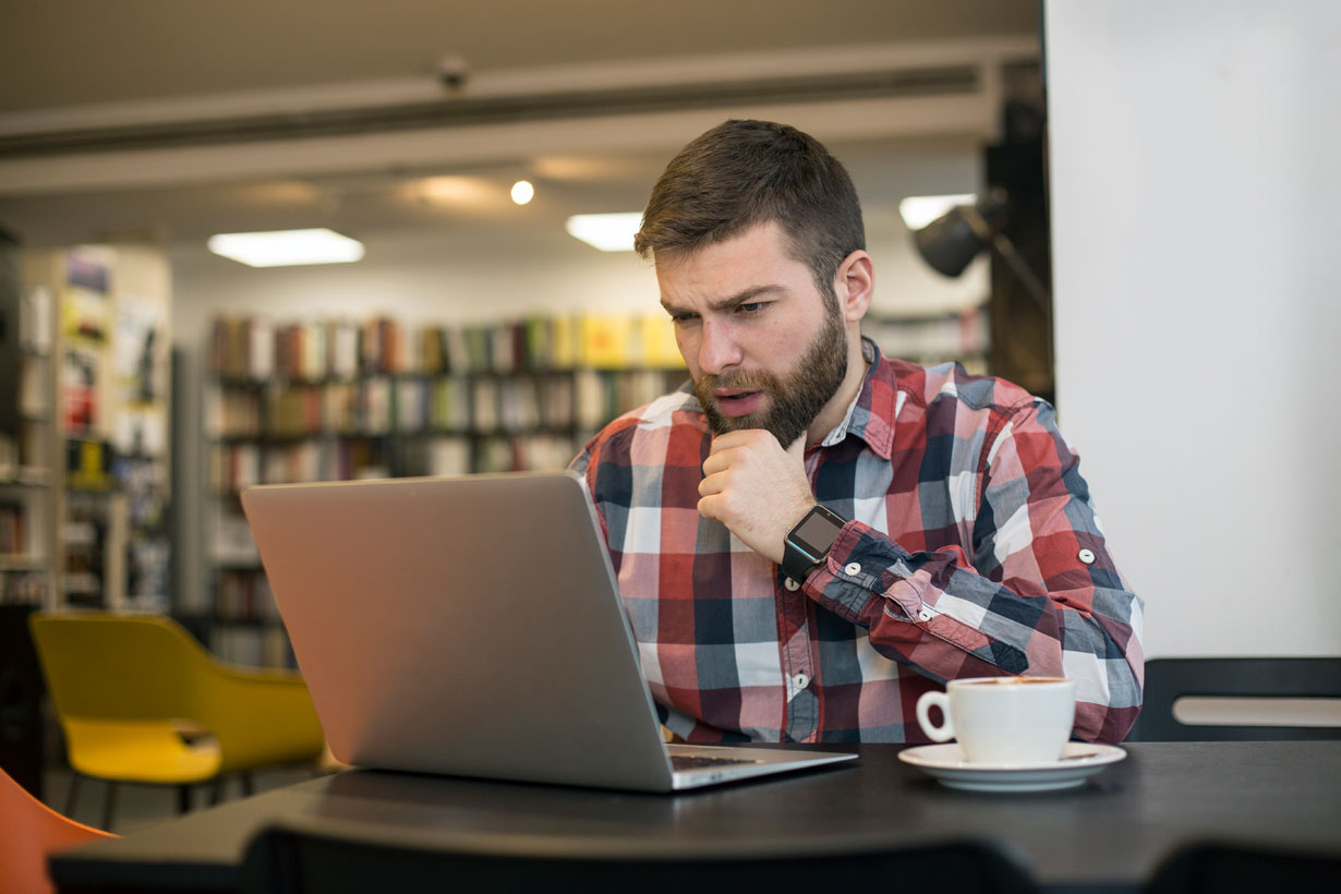 Student looking at laptop in a library