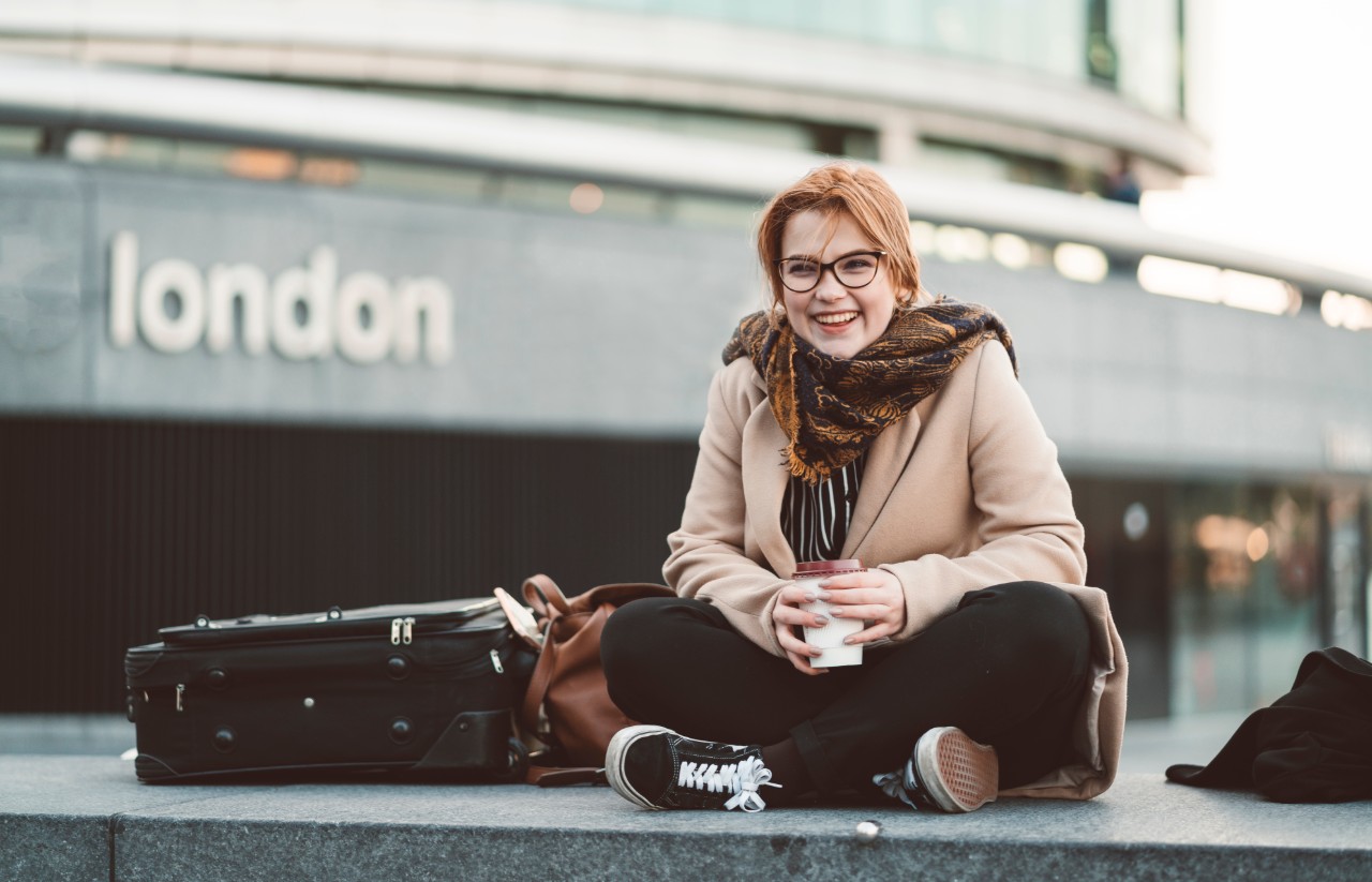 Young woman sat outside a london train station