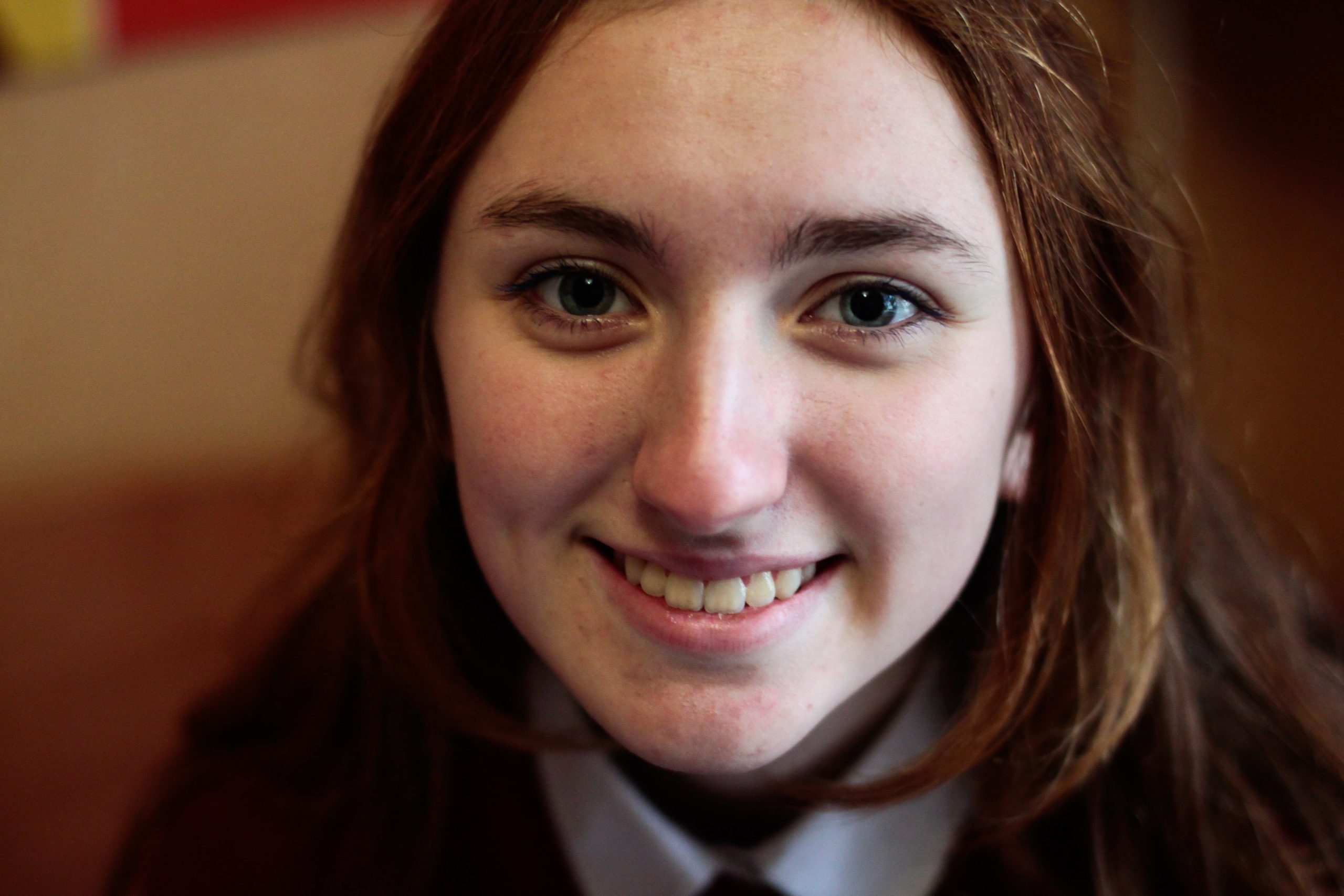 Headshot of a teenager in school uniform smiling