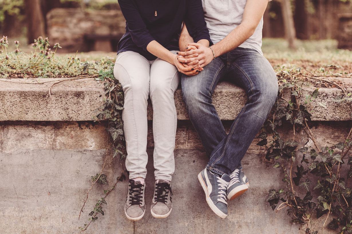 Couple sitting on a wall holding hands