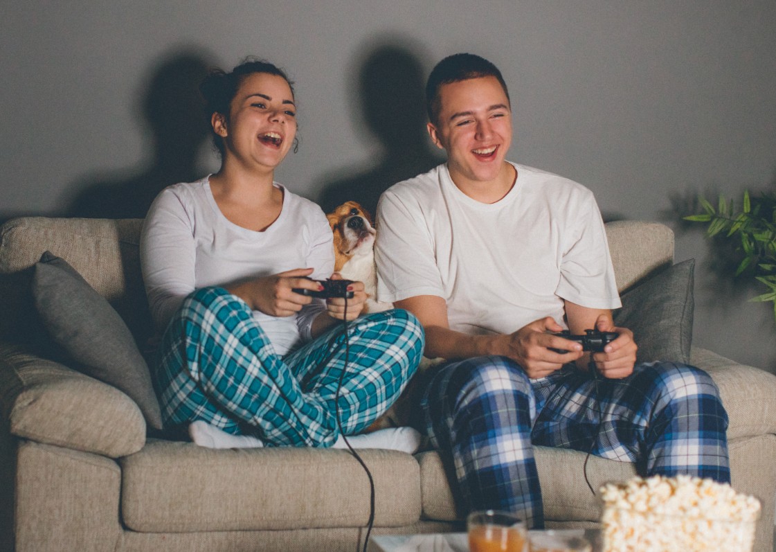 Couple in pyjamas sitting on the sofa playing a video game