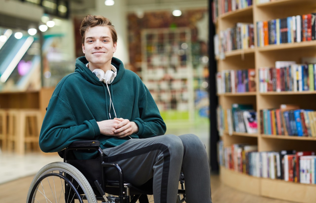 Male student using a wheelchair and in the library