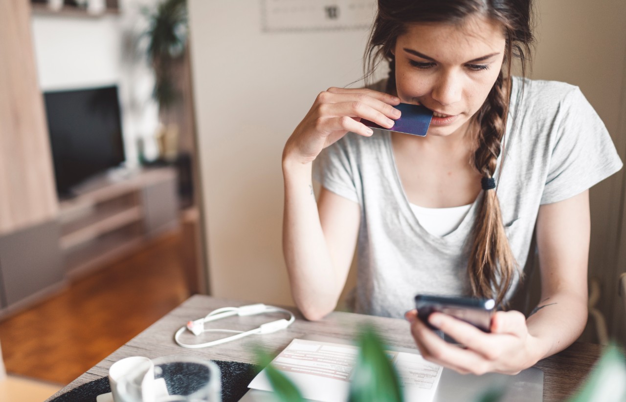 Young woman sat at home with credit card in hand