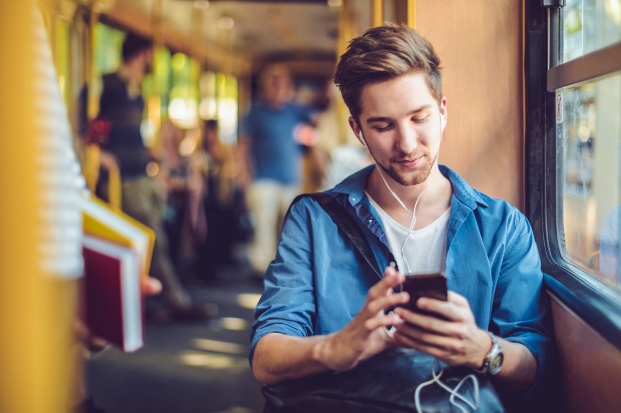 Man travelling on a train, looking at his phone